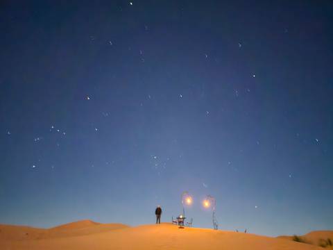       Night sky filled with stars above a lone figure in the quiet desert.
  