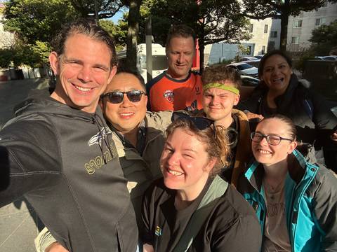       A cheerful selfie shows a travel group smiling brightly in morning sunlight.
  