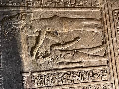       Close-up of ancient Egyptian carved relief depicting a pharaoh blessing a figure.
  