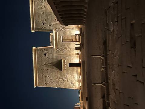       An ancient Egyptian temple illuminated at night, reliefs visible on the facade.
  