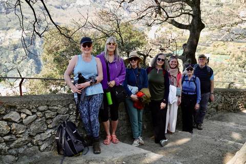       Small hiking group posing by a stone railing with forested valley behind.
  