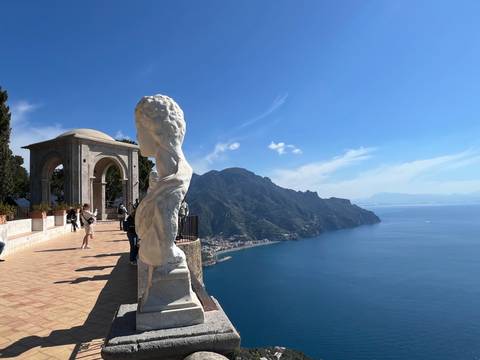       Terrace of Infinity in Ravello with marble statue and sweeping view of the Amalfi coastline.
  