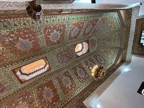       Richly painted and carved wooden ceiling with gold chandelier in a historic palace room.
  