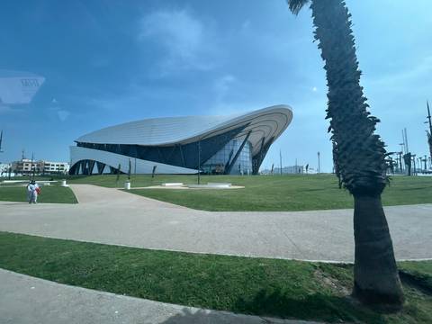       Futuristic glass and steel cultural center surrounded by lawns and palm trees.
  