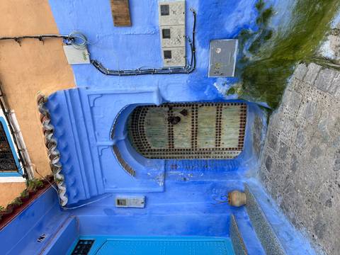       Traditional arched blue doorway with aged wooden door and mosaic studs.
  