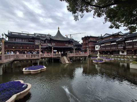       Classical Chinese architecture of Yuyuan Old Street reflected in ponds with tourists crossing wooden bridges.
  