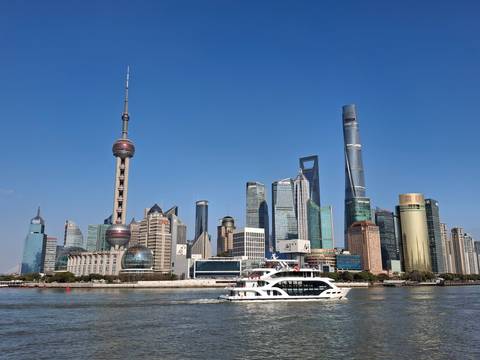       Iconic Shanghai Pudong skyline with Oriental Pearl Tower and modern skyscrapers above the Huangpu River with a passing white ferry.
  