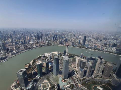       High-altitude daytime panorama of Shanghai overlooking the Huangpu River, Oriental Pearl Tower and countless skyscrapers stretching to the horizon.
  
