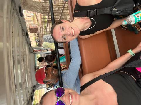       A group of travelers sit inside an open-air shuttle cart, smiling and enjoying their ride during a sightseeing tour.
  