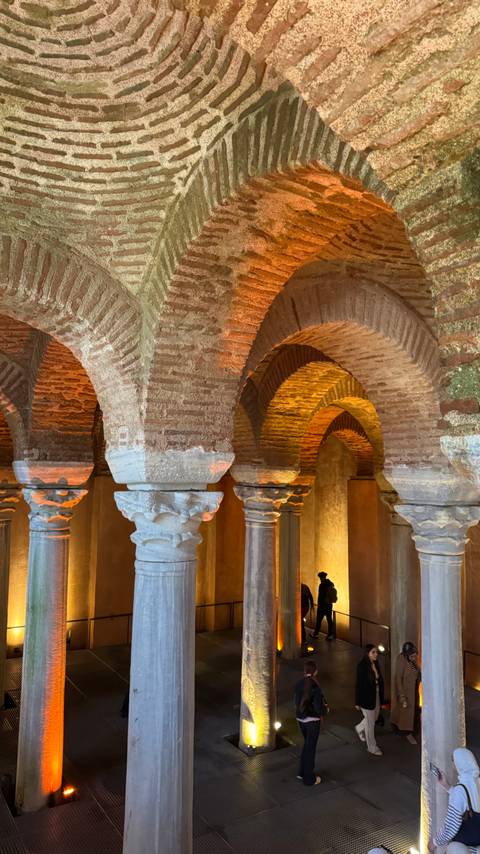       Warmly lit brick and marble columns supporting ancient arches in an underground basilica.
  