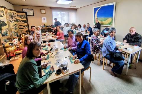       Participants seated at tables during cultural craft workshop indoors
  