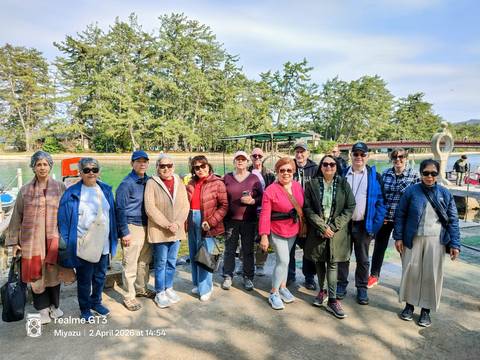       Tour group standing near pier with forested island backdrop in Japan
  