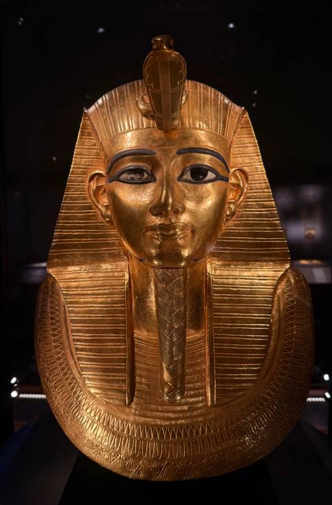       Golden funerary mask glows under museum lighting, showcasing ancient Egyptian craftsmanship.
  