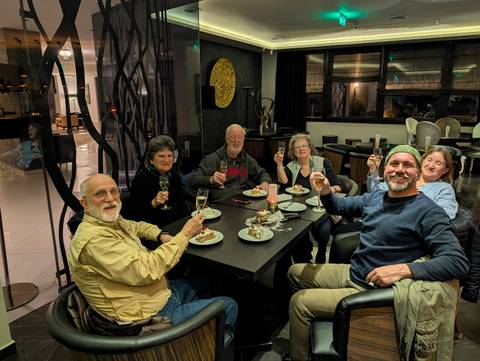       Group of travellers raise champagne glasses in a hotel lounge celebrating after dinner.
  