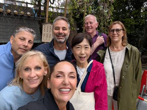       Smiling tour group taking a close-up selfie in a garden shrine setting
  