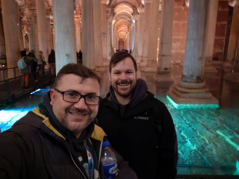       Smiling travelers take a selfie inside Istanbul’s illuminated Basilica Cistern.
  