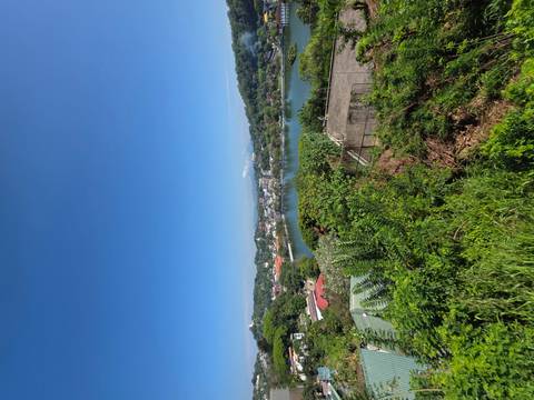       Panoramic view over a lake and Kandy town with clear blue sky and distant hills.
  