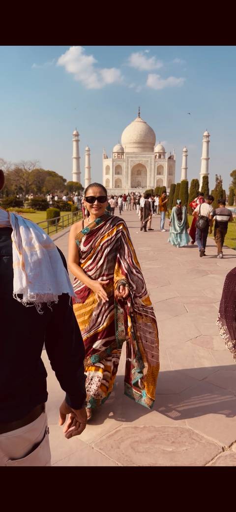       Woman in colorful sari posing among a crowd on the grounds leading to a major Indian monument
  
