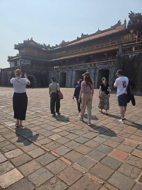       Group of visitors walking toward the main gate of the Imperial City in Hue on a sunny morning
  