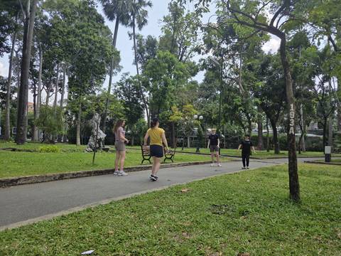       Travelers playing or exercising along a shaded pathway in a green urban park
  