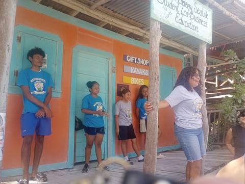      Local youth standing outside a colorful gift shop and kayak rental on Caye Caulker
  
