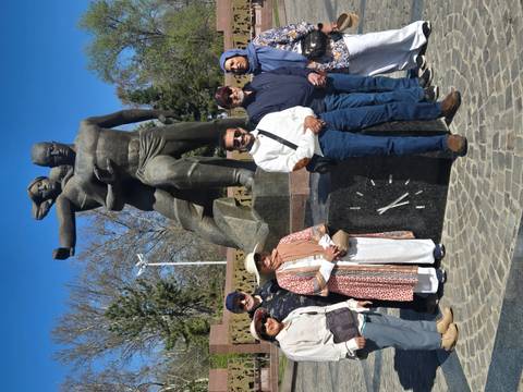       Travellers stand in front of a dynamic bronze war memorial statue on a sunny day.
  
