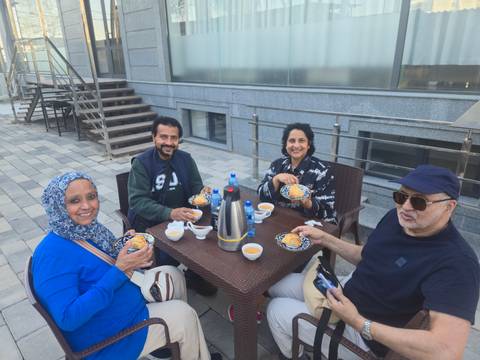      Four friends enjoy tea and pastries at an outdoor rooftop terrace.
  