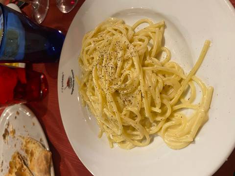       Close-up of a creamy spaghetti dish topped with cracked pepper on a restaurant table
  
