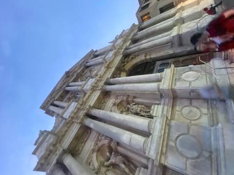       Upward angled shot of a classical stone façade taken at dusk with motion blur in the foreground
  