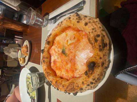       Freshly baked Margherita pizza with melted cheese and basil on a restaurant table
  
