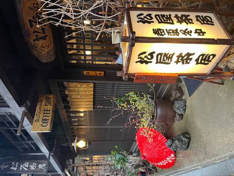       Cozy traditional storefront with wooden lattice, hanging lantern and sign for a coffee shop on a rainy street.
  