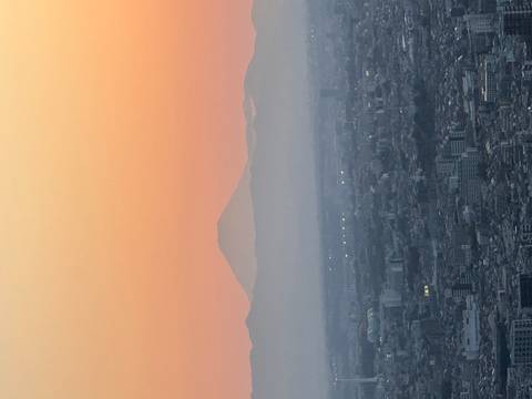       Silhouette of Mount Fuji rising above Tokyo cityscape at colorful dawn.
  