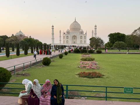       Wide garden view of the Taj Mahal with flowerbeds and visitors at twilight.
  