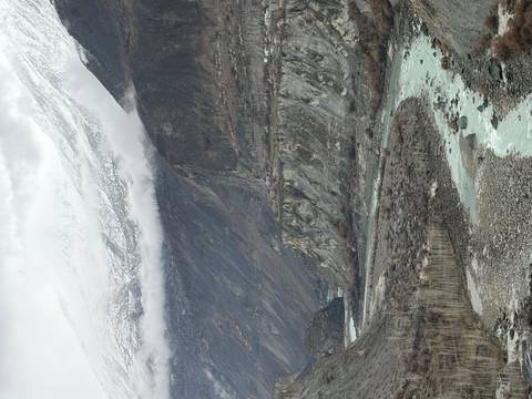       Winding river cutting through dramatic snow-capped mountains under low clouds
  