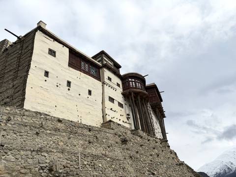       Angled view of ancient fort walls and wooden balconies under grey sky
  