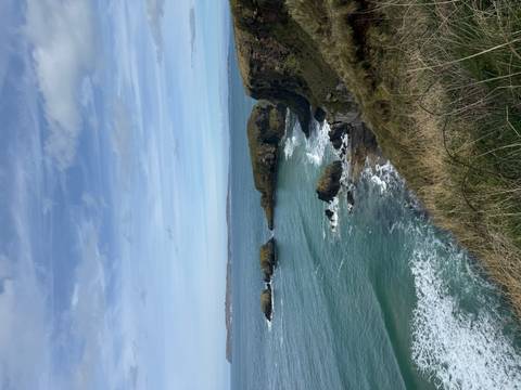       Rocky sea arches and islets surrounded by turquoise waves beneath a partly cloudy sky on Ireland’s coast.
  