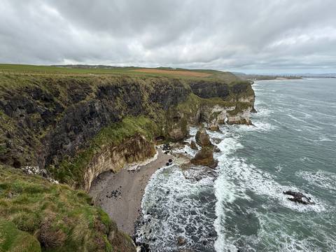       High view over rugged cliff formations and wild Atlantic surf along the Northern Irish coast.
  