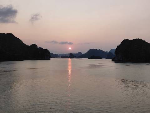       Serene sunset over karst limestone islands reflecting on calm bay waters.
  