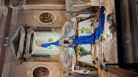       An ornate church altar is decorated with blue fabric, wheat and desert plants.
  