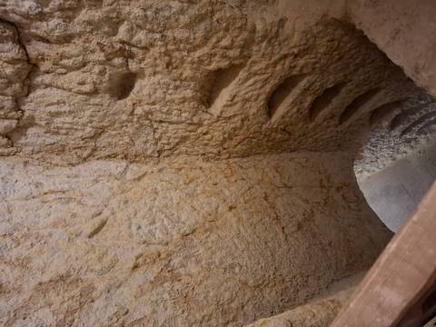      Rough-hewn spiral stairs carved into soft rock descend into an underground chamber.
  