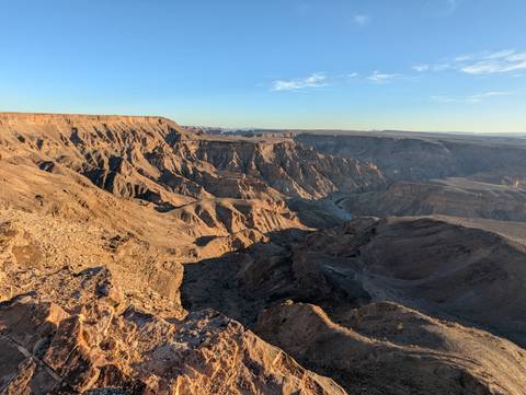       Sun-lit layers of a massive desert canyon with rugged ridges and deep shadows.
  