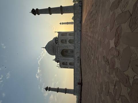       The Taj Mahal silhouetted against a golden dawn sky, viewed from the main forecourt.
  