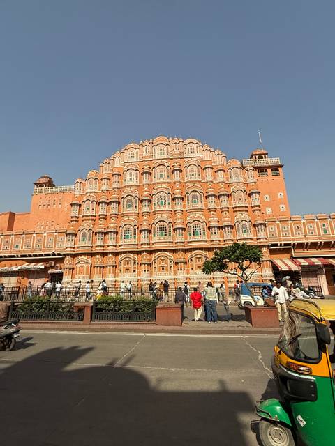       The ornate pink façade of Hawa Mahal rises above bustling street life in Jaipur.
  