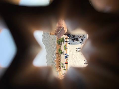       An elevated view of a fort courtyard and distant hills framed through a decorative lattice window.
  