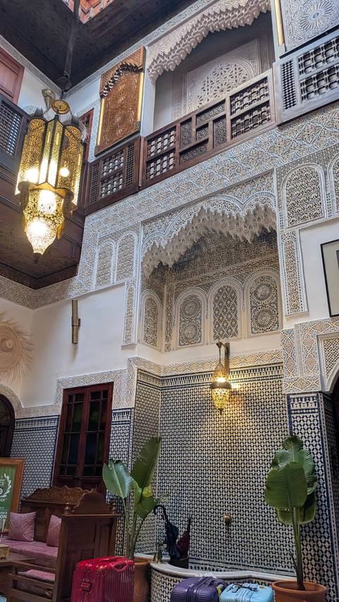       Exquisite Moroccan riad interior with ornate plaster carvings, mosaic tiles and hanging lantern
  