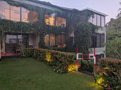       Modern villa covered in cascading vines with a lit garden at dusk.
  