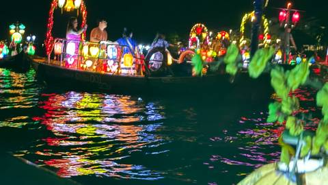       Colorful lantern boats reflecting on water during night festival ride
  