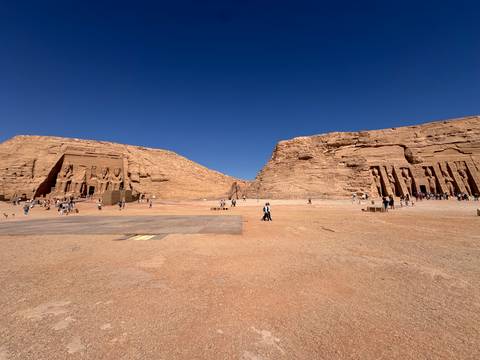       Twin rock-cut temples of Abu Simbel rise from desert plain under deep blue sky
  