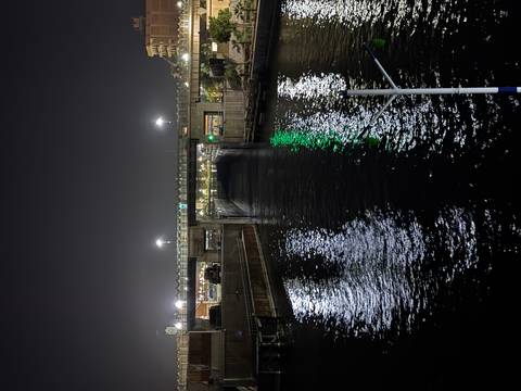       Nighttime view of illuminated lock gate and bridge reflected in dark waters
  