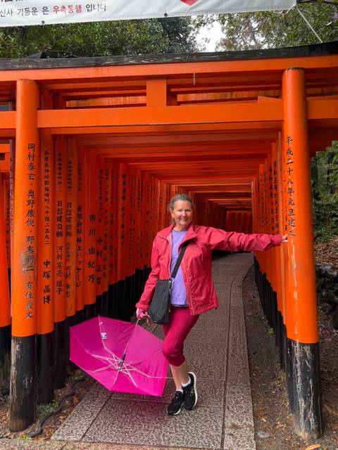       Traveler stands among endless vermilion torii gates at Fushimi Inari shrine.
  